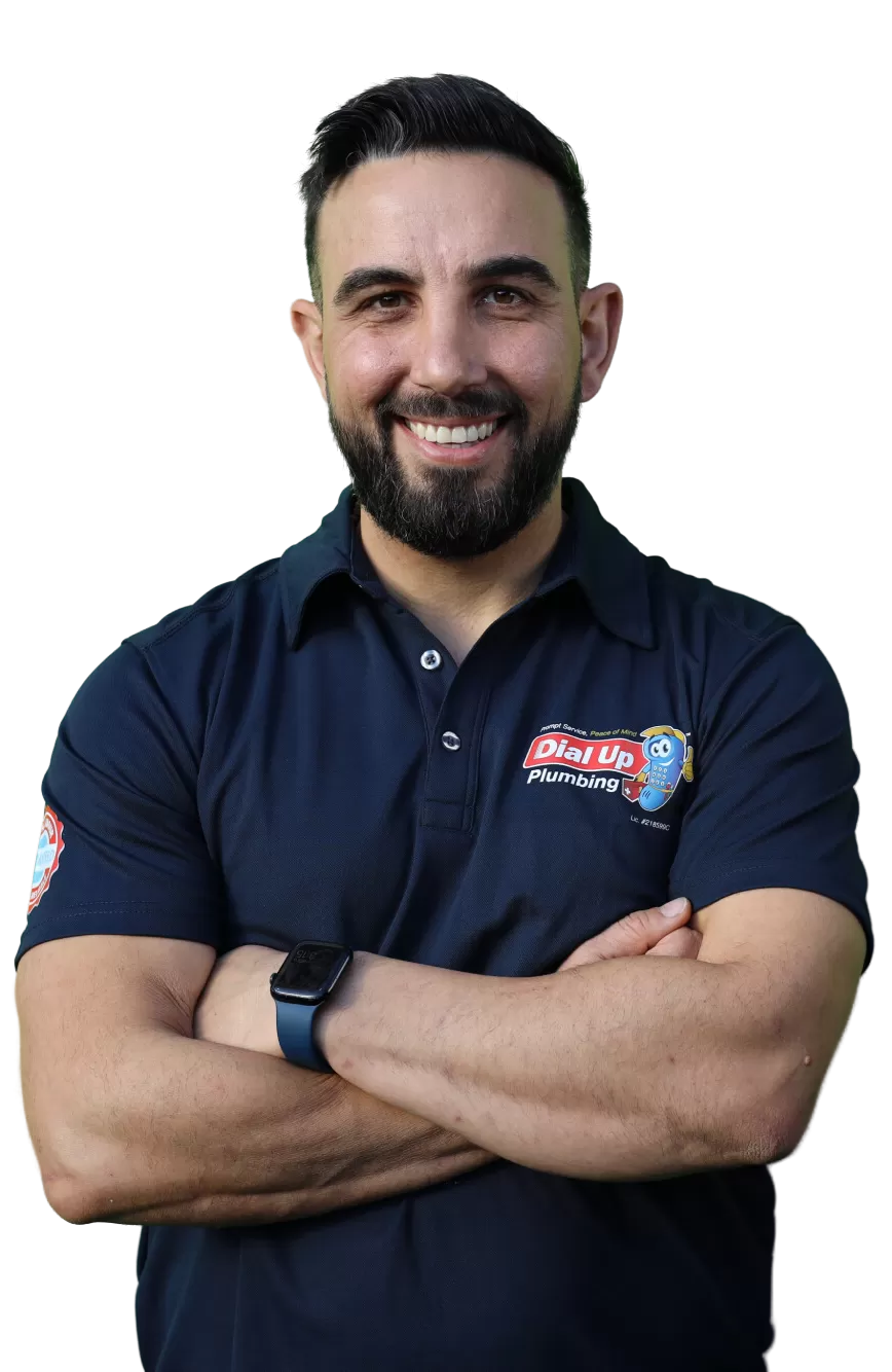 Smiling man with beard in a navy blue "Dial Up Plumbing" shirt with folded arms, wearing a black smartwatch.